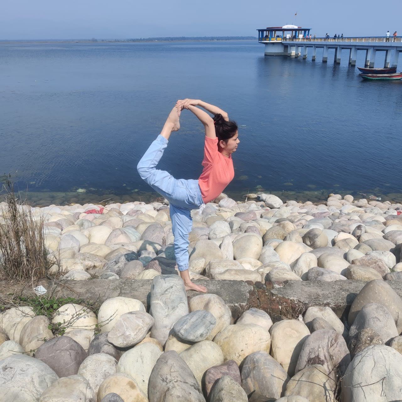 A person practicing yoga outdoors with a scenic view, representing future physical studio in Pilibhit.